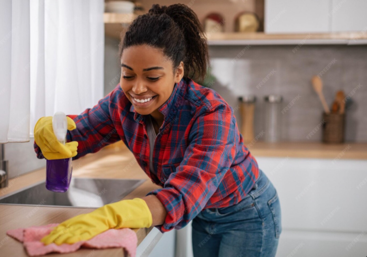 Cheerful domestic worker wiping the kitchen counter